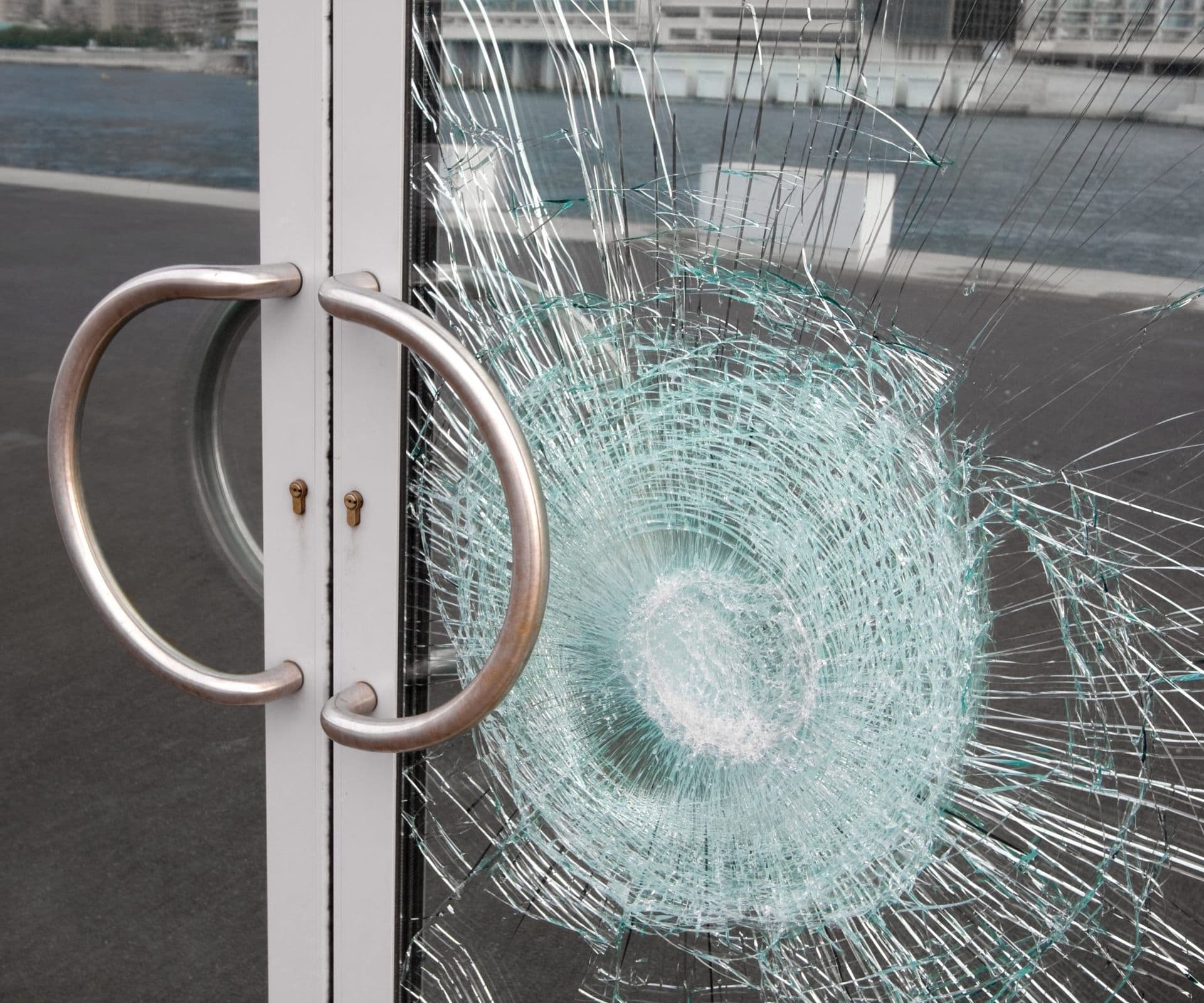 Broken window on business glass door shattered by vandalism